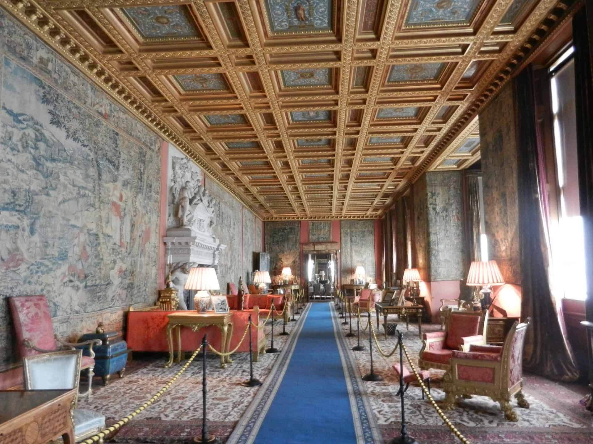 Longleat House Opulent historic royal palace interior with ornate gold ceiling, antique furniture, decorative tapestries, and classic lighting, showcasing luxury and heritage in England.