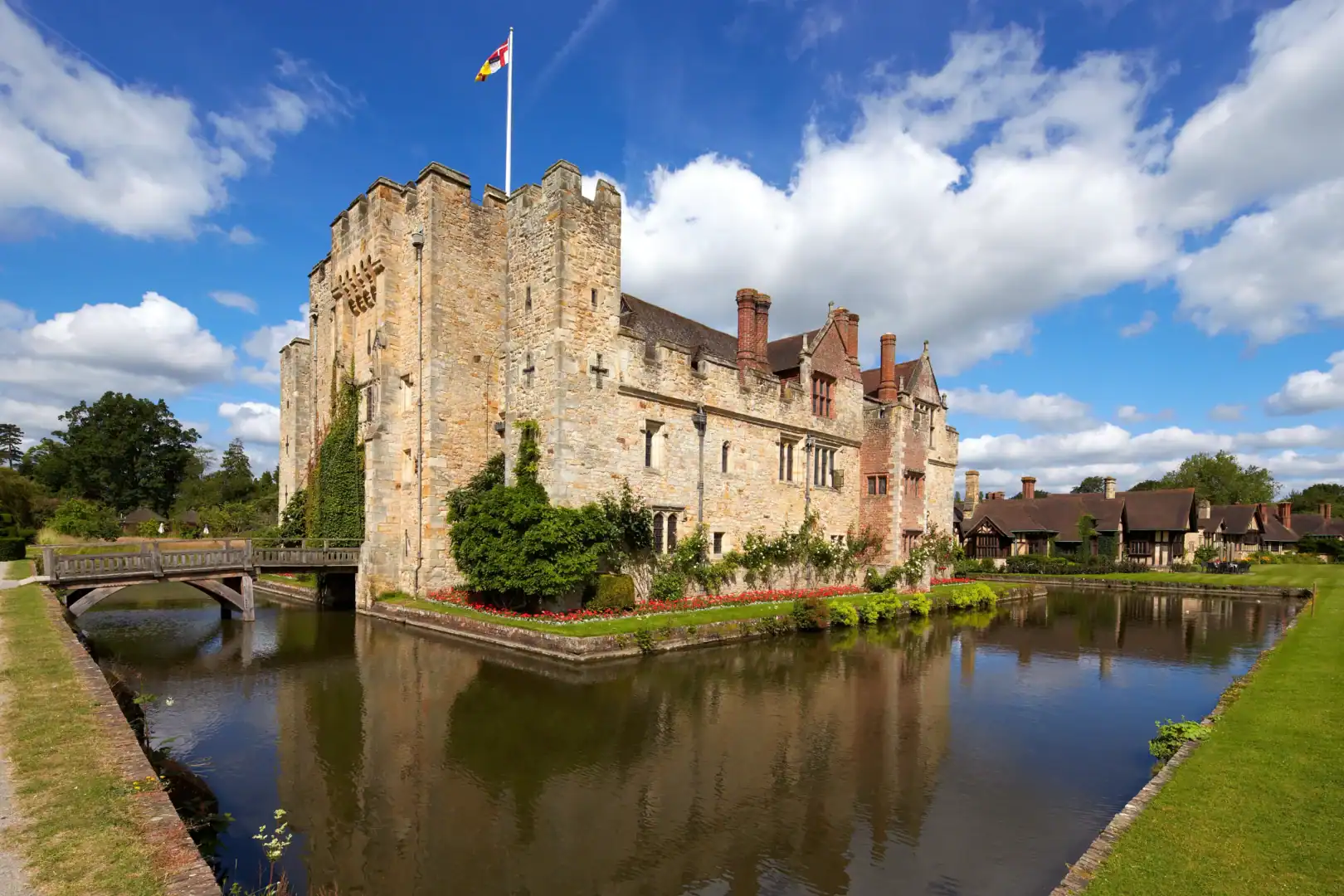 Historic medieval castle surrounded by moat and lush gardens in the UK, showcasing iconic castle architecture and scenic landscape.