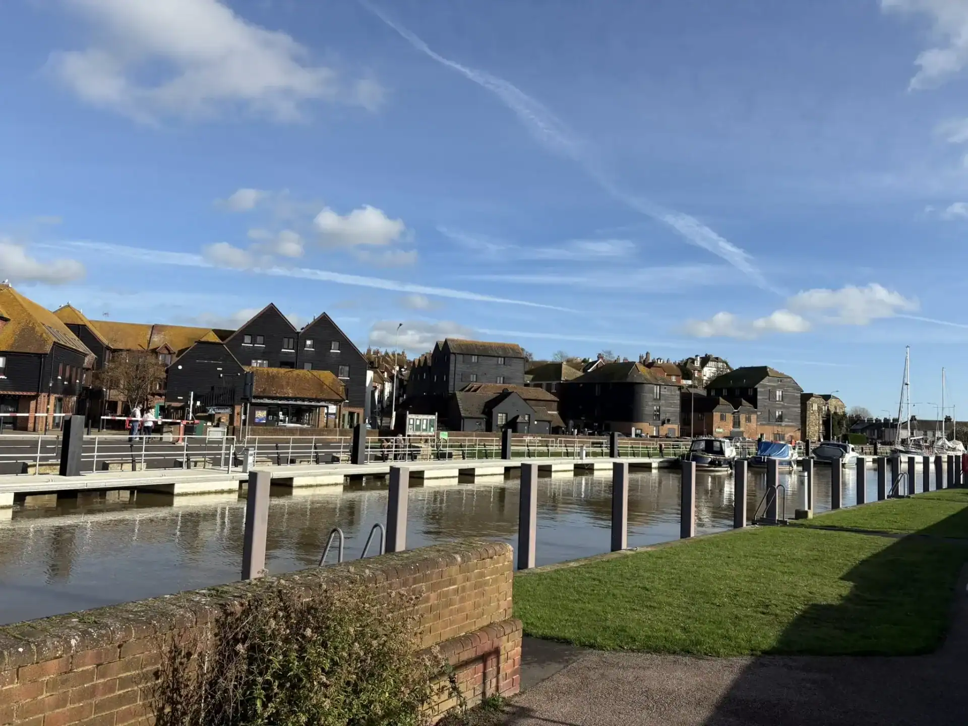 Picturesque lakeside town in the UK with modern black wooden houses and boats docked, perfect for scenic cruises, sightseeing, and relaxing waterfront experiences.